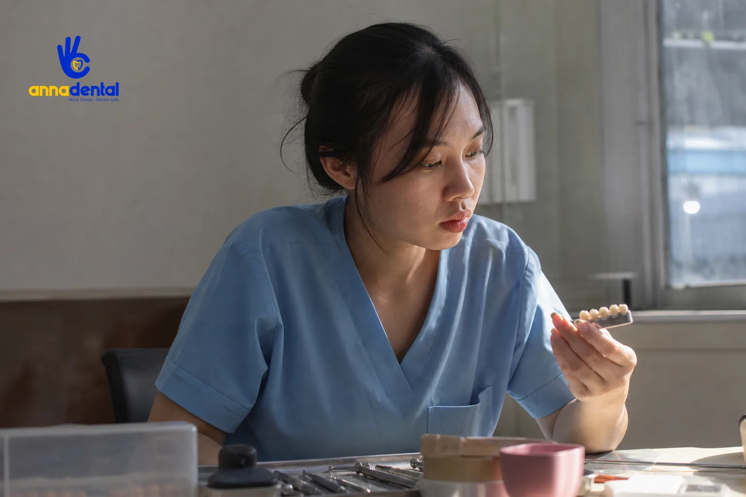 Nữ bác sĩ xem xét mẫu các loại răng sứ toàn sứ khác nhau